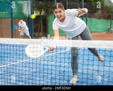 Junge sportliche Frau spielt Paddle Tennis im Freien Stockfoto