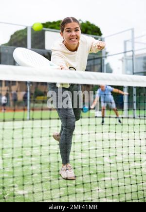 Junge sportliche Frau spielt Paddle Tennis im Freien Stockfoto