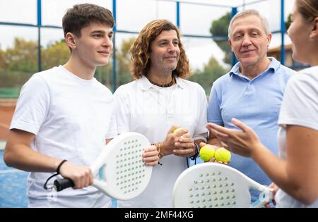 Vier Paddle-Tennisspieler sprechen auf dem Platz Stockfoto