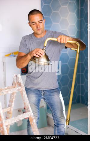 Professioneller Handwerker, der im Badezimmer mit einem Duschkopf im Innenbereich arbeitet Stockfoto