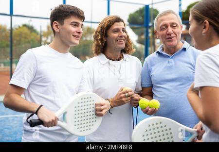 Vier Paddle-Tennisspieler sprechen auf dem Platz Stockfoto