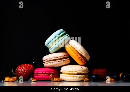 Bunte Makronen-Kuchen. Kleine französische Kuchen. Süße und bunte französische Makronen. Viele leckere Makronen mit frischen Beeren, Himbeeren und Blaubeeren, Stockfoto