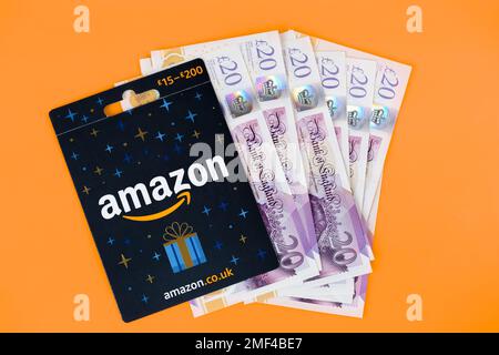 Amazon-Geschenkgutschein, der auf einen Bargeldstapel gelegt wird. Stafford, Großbritannien, 24. Januar 2023 Stockfoto