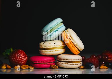 Bunte Makronen-Kuchen. Kleine französische Kuchen. Süße und bunte französische Makronen. Viele leckere Makronen mit frischen Beeren, Himbeeren und Blaubeeren, Stockfoto