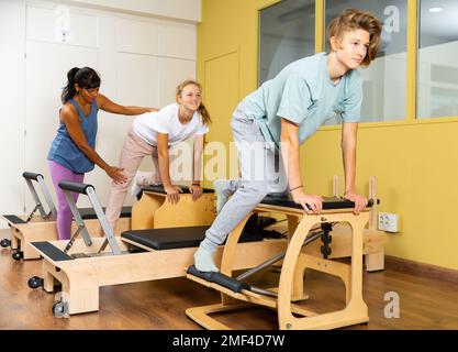 Kleiner Junge und Mädchen mit Pilates-Trainer im Fitnessstudio Stockfoto