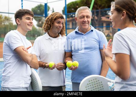 Vier Paddle-Tennisspieler sprechen auf dem Platz Stockfoto