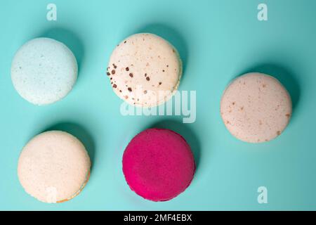 Bunte Makronen. Kleine französische Kuchen. Süße und farbenfrohe französische Makronen auf blauem Hintergrund. Geschenk zum Valentinstag Stockfoto