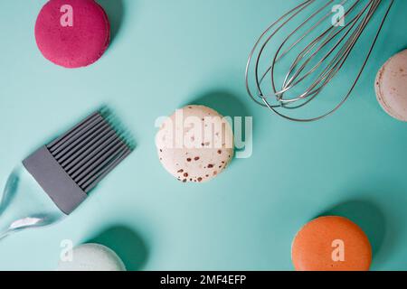Bunte Makronen. Kleine französische Kuchen. Kochen, Schneebesen, gebrochene Makronen, Früchte, Erdbeeren, Himbeeren und Brombeeren. Kochen auf blauem Boden Stockfoto