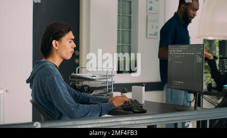 Junior Developer schreibt Datenbankcode, um eine neue Benutzeroberfläche auf dem Computerbildschirm zu erstellen, Server-Sicherheitscodierung. Programer arbeitet an Software-App-Algorithmen in der IT-Firmenzentrale. Stockfoto