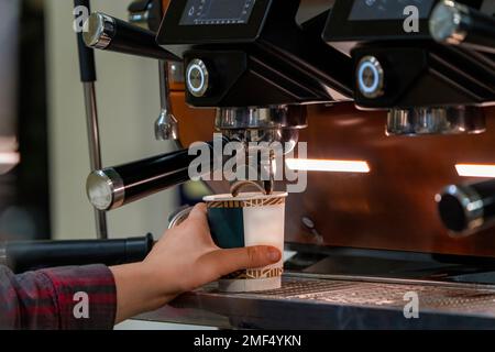 Barista schäumt Milch auf, um Kaffee zuzubereiten. Barista Hände vor der Kaffeemaschine Stockfoto