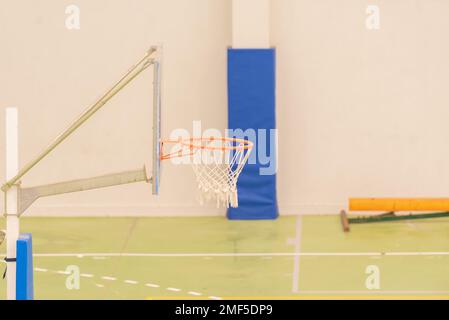 Seitenansicht eines Basketballkörpers in einem Mini-Basketballkorb auf einem Platz ohne Parkett in grüner Farbe Stockfoto