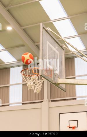 Seitenansicht eines Basketballkörpers in einem Mini-Basketballkorb auf einem Platz ohne Parkett in grüner Farbe Stockfoto