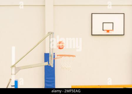 Seitenansicht eines Basketballkörpers in einem Mini-Basketballkorb auf einem Platz ohne Parkett in grüner Farbe Stockfoto