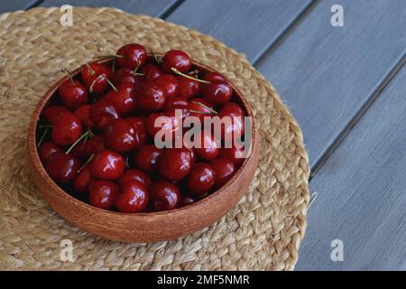 Frische Kirschen in einer Holzschüssel auf einem grauen Tisch Stockfoto