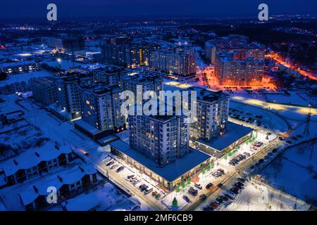 Nächtliche Winterstadt mit beleuchteten Straßen. Stadtbild, Blick auf die Drohne. Nachtlandschaft Stockfoto