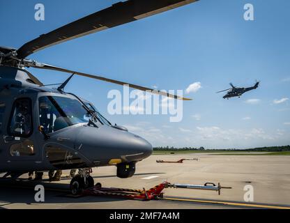 Ein MH-139A Grey Wolf sitzt auf der Fluglinie, während ein anderer am 17. August auf der Eglin Air Force Base, Florida fliegt. Der ausgestellte Grey Wolf Flug war der erste Flug seit der Übernahme des Flugzeugs durch die Air Force am 12. August. Es war auch der erste All-Air-Force-Personalflug im neuesten Hubschrauber der Air Force. (USA Luftwaffe Foto/Samuel King Jr.) Stockfoto