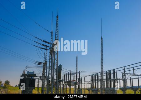 Elektrizität und Energie.Kraftwerk in den Sonnenstrahlen auf blauem Hintergrund.Energieanlagen.Hochspannungsenergie. Stromleitung. Stockfoto