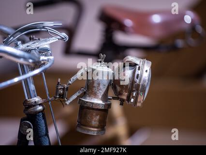 Wismar, Deutschland. 24. Januar 2023. Eine Hartmetalllampe hängt an einem der historischen Fahrräder in der neuen Dauerausstellung von mehr als 50 historischen Fahrrädern im Phantechnikum. Das seltene Fahrrad war seit Jahrzehnten verloren und wurde erst vor ein paar Jahren im Garten eines Modehauses wieder aufgetaucht. Das Technologiemuseum wird am 25. Januar 2023 als Erweiterung seiner Dauerausstellung einen Schwerpunkt auf die technische und kulturelle Geschichte des Fahrrads legen. Die Fahrräder aus der Sammlung eines Sammlers aus Wismar veranschaulichen Meilensteine der Fahrradgenese und verbinden sie mit wi Credit: dpa/Alamy Live News Stockfoto