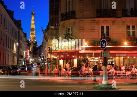 Nachtsicht auf den Eiffelturm und das Café Le Recrutement an der Ecke Rue Saint-Dominique und Boulevard de la Tour-Maubourg mit Rücklichtpfaden. Paris. Frankreich Stockfoto