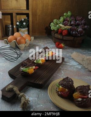 eclairs mit Sahne und Obststücken auf frischem Obsthintergrund Stockfoto