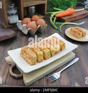 Omelette wird auf einem weißen Tablett mit frischen Eiern und Gewürzen serviert Stockfoto