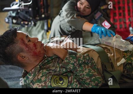 Ein simulierter Patient wird von einem Mitglied des medizinischen Teams der Royal Malaysian Air Force während eines Massenverletzten und flugmedizinischen Evakuierungsszenarios zur Unterstützung von Training Pacific Angel am Luftwaffenstützpunkt Kuantan, Malaysia, 18. August 2022 betreut. Pacific Angel war eine einwöchige multilaterale Übung, bei der 370 Teilnehmer aus sechs Ländern zusammenkamen, um die Zusammenarbeit und Interoperabilität bei humanitären Hilfseinsätzen und Katastrophenhilfemaßnahmen zu fördern. Stockfoto