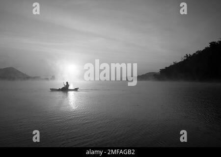 Frauen auf Kajak-Reihen im Stausee während des Sonnenaufgangs, Harirak Waldpark Huai Nam man Stausee Loei Thailand 21. Januar 2023 Stockfoto