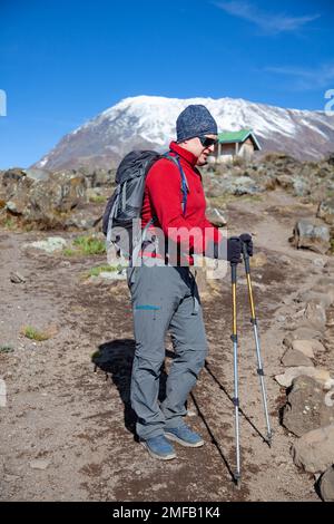 Männlicher Rucksacktourist auf der Wanderung zum Kilimandscharo-Berg. Stockfoto