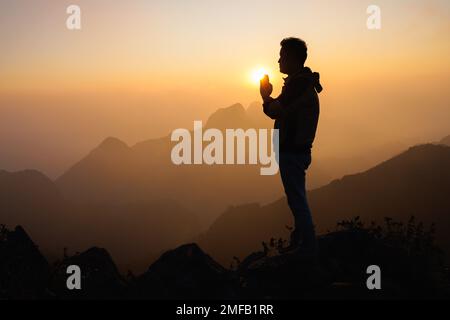 Silhouette eines Mannes betet zu gott auf dem Berg. Betet Hände, achtet. Stockfoto