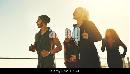 Freunde sorgen für zusätzliche Motivation. Eine Fitnessgruppe, die auf der Promenade läuft. Stockfoto