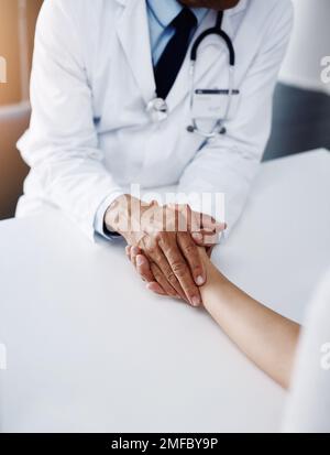 Keine Sorge, wir werden uns gut um Sie kümmern. Ein nicht wiedererkennbarer Arzt, der einen Patienten an der Hand hält, um ihn zu trösten und ihm zu helfen, sich wohl zu fühlen. Stockfoto