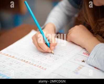 Sie ist eine akribische Arbeiterin. Nahaufnahme eines nicht identifizierbaren Grundschulmädchens, das im Unterricht in ihr Notizbuch schreibt. Stockfoto