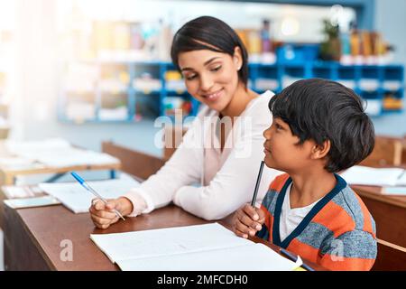 Du kannst es bekommen, wenn du dich darauf konzentrierst. Eine fröhliche Lehrerin, die einer Schülerin in der Schule hilft. Stockfoto