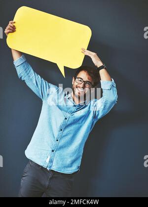Es ist an der Zeit, zu sagen, was du denkst. Studioporträt eines jungen Mannes, der eine Sprachblase vor grauem Hintergrund hält. Stockfoto