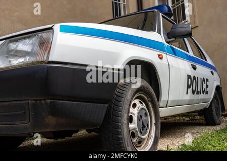 Ein alter Polizeiwagen steht vor einem Gebäude mit versperrten Fenstern Stockfoto