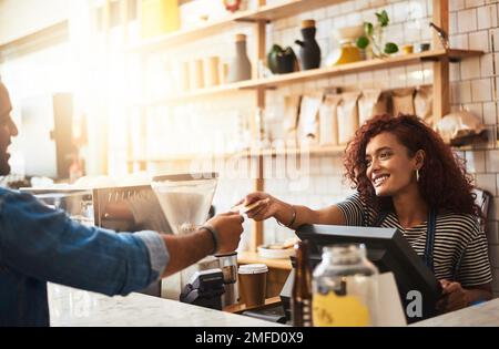 Danke, dass Sie im besten Café der Stadt vorbeischauen. Eine Kellnerin, die eine Kreditkartenzahlung von einem Gast in einem Café akzeptiert. Stockfoto