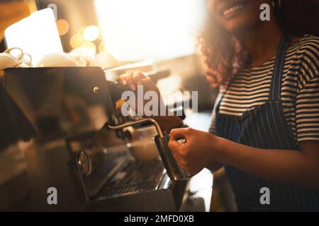 So wird ein Becher Magie gemacht. Nahaufnahme eines Baristas, der eine Kaffeemaschine in einem Café bedient. Stockfoto