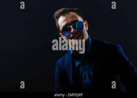 Porträt eines attraktiven, fröhlichen Gentleman, der isoliert vor dunklem Hintergrund posiert Stockfoto
