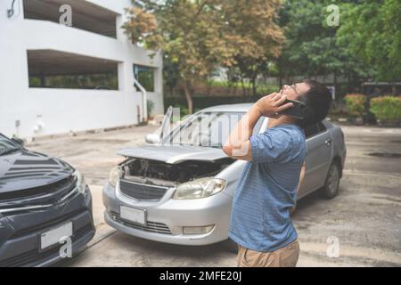 Ein Mann meldet Autounfallschäden und ruft die Versicherung an und beansprucht den Pannendienst Stockfoto