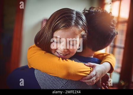 Ich liebe dich immer, Dad. Ein kleines Mädchen umarmt ihren Vater zu Hause. Stockfoto