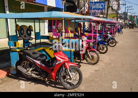 Typische Tuk Tuks von Koh Lanta. Motorradtaxis im Cartoon-Stil mit Beiwagen, die hintereinander geparkt sind. Ko Lanta, Krabi, Thailand. 30. November 2022. Stockfoto