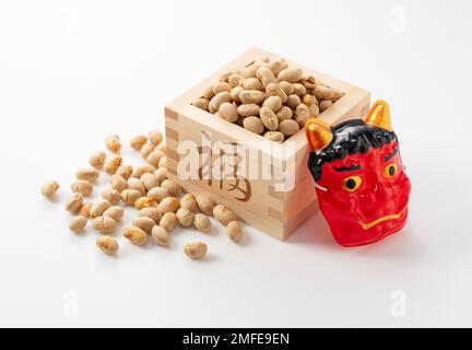 Bohnen zum Bohnenwerfen und Masken von Ogern auf weißem Hintergrund. Japanische Oger. Setsubun-Bild. Stockfoto