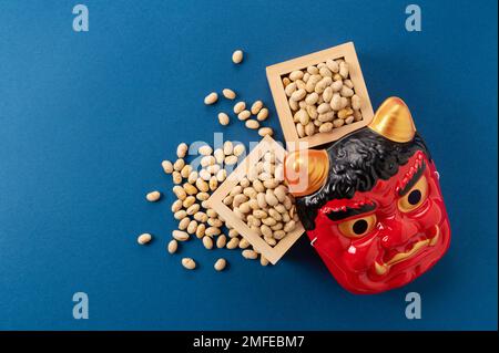 Bohnen zum Bohnenwerfen und Masken von Ogern auf marineblauem Hintergrund. Japanische Oger. Setsubun-Bild. Stockfoto