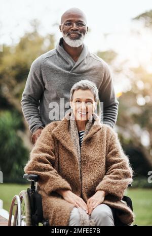 Er hat sie nach all den Jahren immer noch zurückbekommen. Ein älterer Mann schubste seine Frau im Rollstuhl vor ihr Haus. Stockfoto