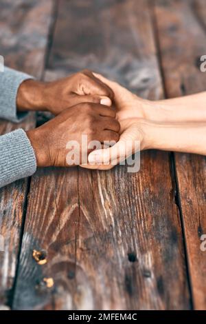 Halt dich fest, woran du glaubst. Zwei nicht wiedererkennbare Menschen, die Händchen halten. Stockfoto