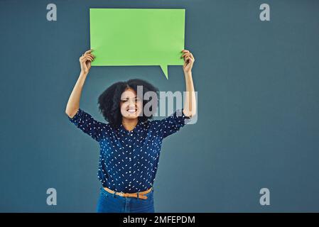 Das ist etwas, worüber man sprechen sollte. Studioaufnahme einer jungen Frau, die eine leere Sprechblase vor grauem Hintergrund hält. Stockfoto