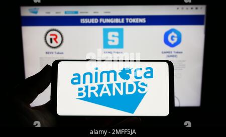 Person, die ein Smartphone mit dem Logo des Softwareunternehmens Animoca Brands Corporation Ltd. Auf dem Bildschirm vor der Website hält. Konzentrieren Sie sich auf das Display des Telefons. Stockfoto