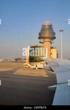 Flugzeuglandung am Hong Kong International Airport, Chek Lap Kok, mit Flugverkehrskontrollturm. Flugzeugflügel beim Ankommen und Business Jet Stockfoto