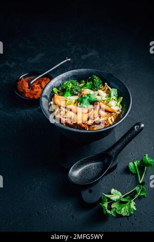 Vegane Miso- oder Ramen-Suppe mit Pilzen und Gemüse auf schwarzem Hintergrund Stockfoto