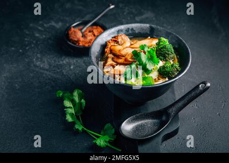 Vegane Miso- oder Ramen-Suppe mit Pilzen und Gemüse auf schwarzem Hintergrund Stockfoto